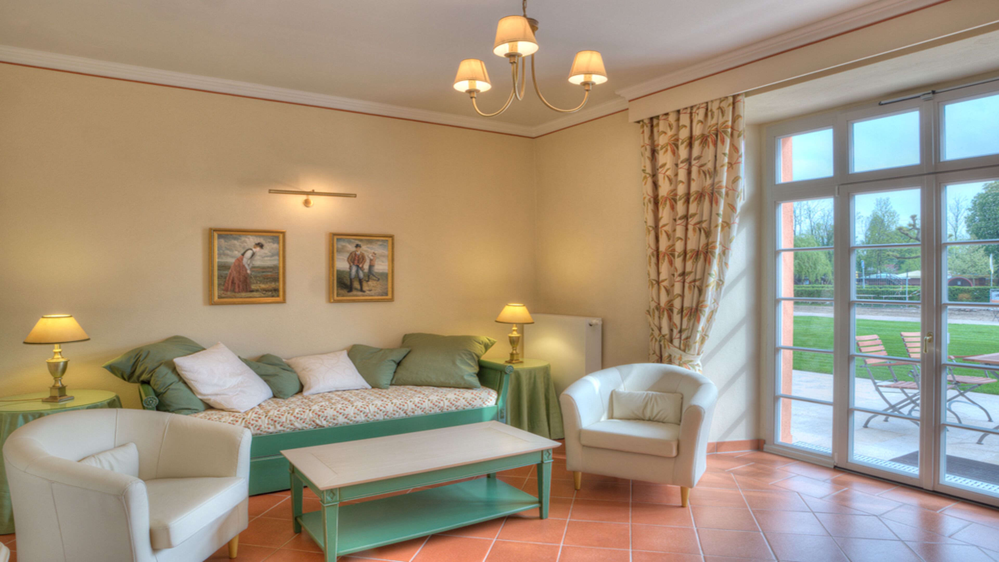 A room with a bed, two chairs, a table, a lamp, and a painting on the wall.