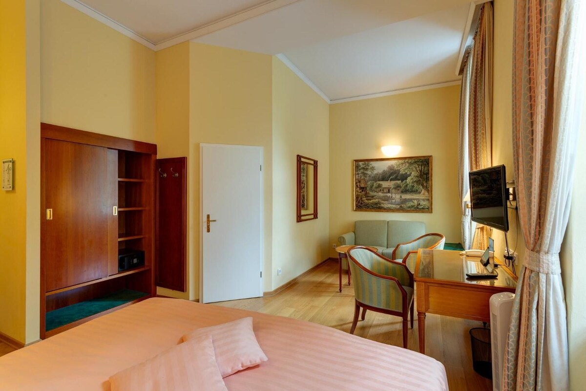Habitació d'hotel amb llit, escriptori, cadira, televisió i un quadre a la paret.