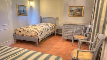 Un dormitorio con cama, cómoda, silla y dos lámparas de pared.