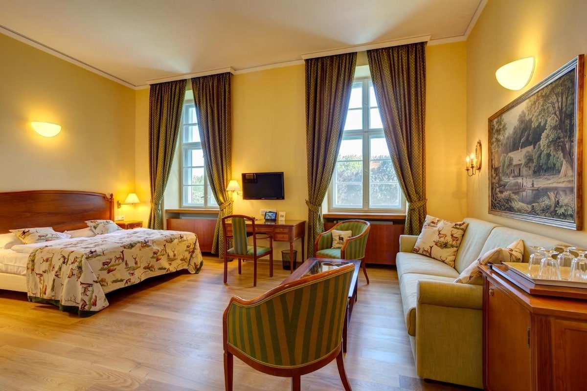 Une chambre d’hôtel avec deux lits, un bureau, une chaise, un canapé et un tableau au mur.