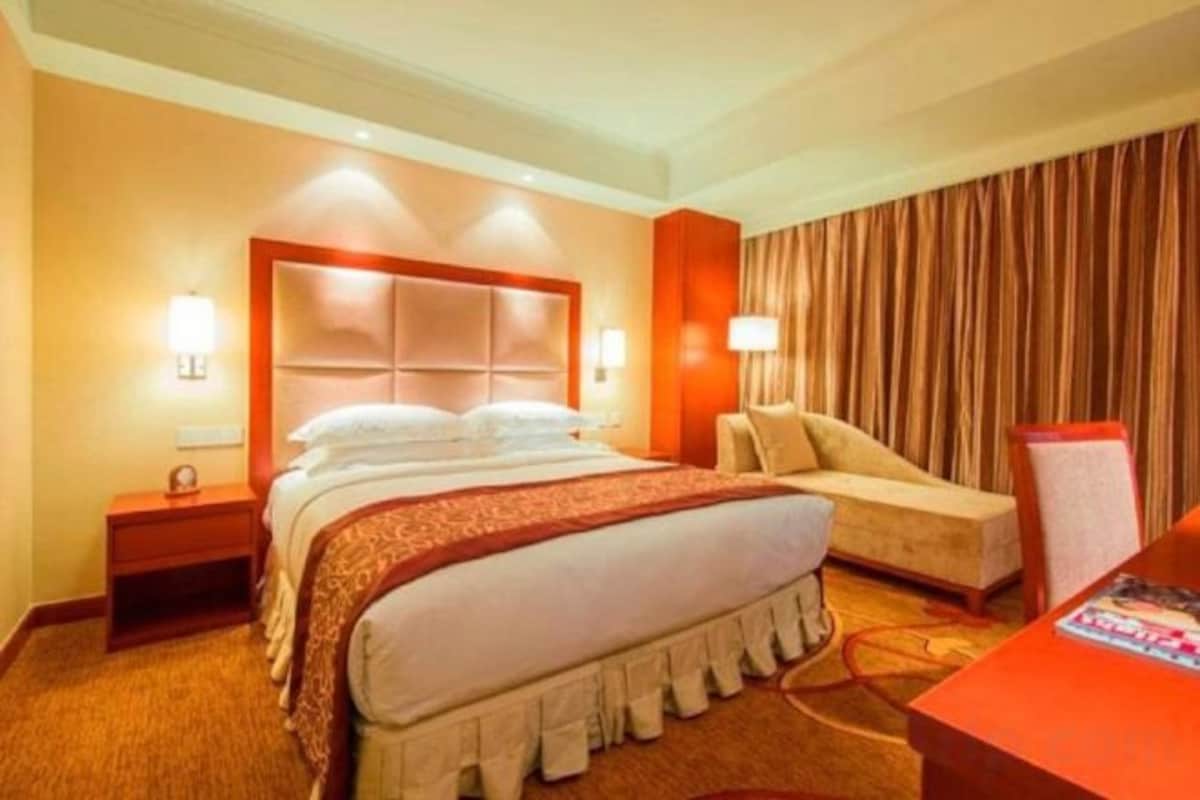 A hotel room with a large bed, bedside tables, a desk, and a chair.