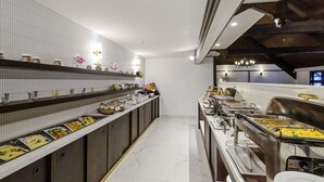 Een buffetopstelling met verschillende stations en een lange toonbank met gerechten.