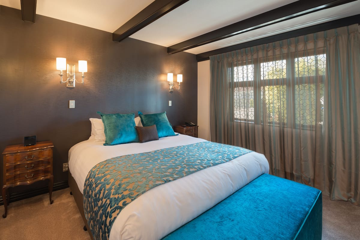 Un dormitorio con una cama grande, dos mesitas de noche y un ventanal con cortinas.