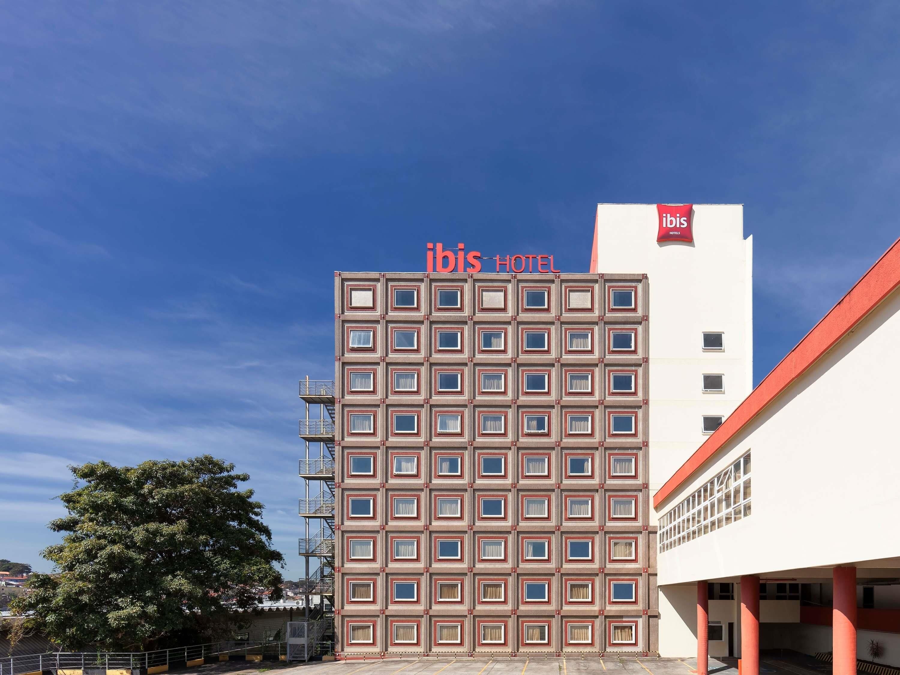 Un edificio de hotel con una cuadrícula de ventanas y un cartel que dice 'ibis HOTEL' en la fachada.