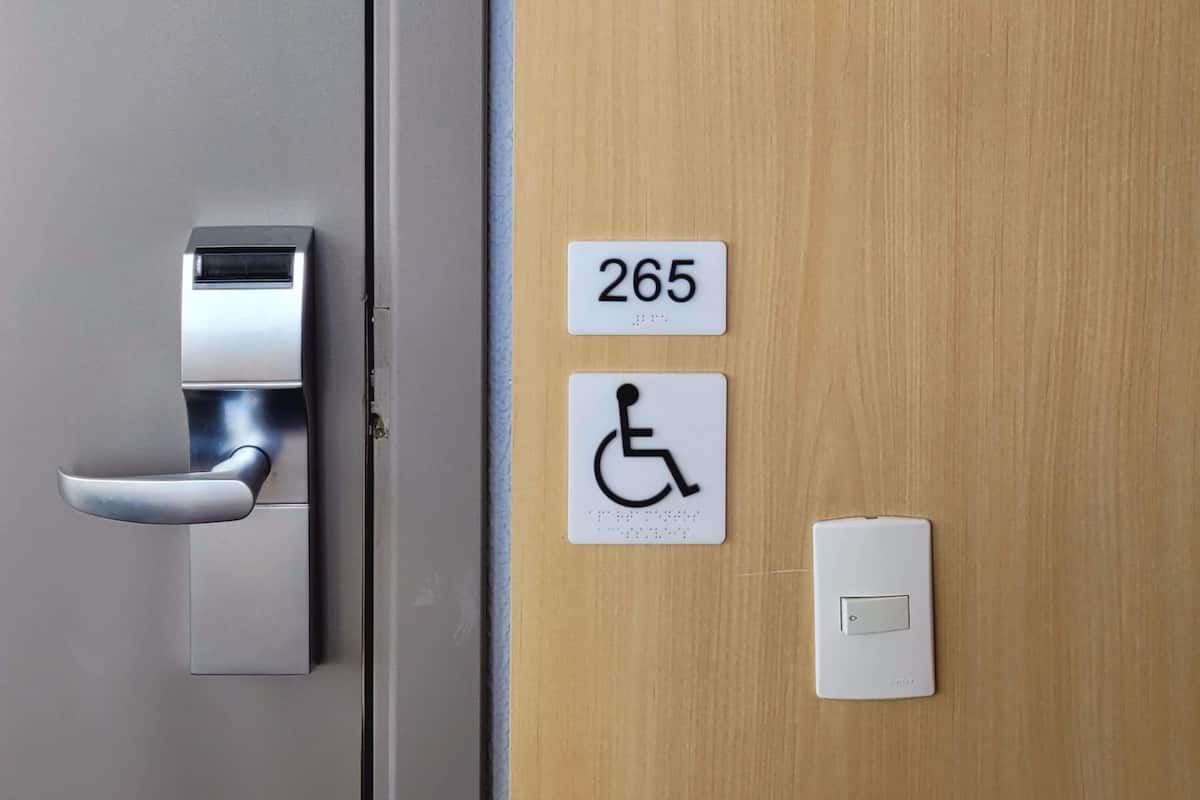 A door with a keycard reader, a wheelchair accessibility sign, and a room number sign.