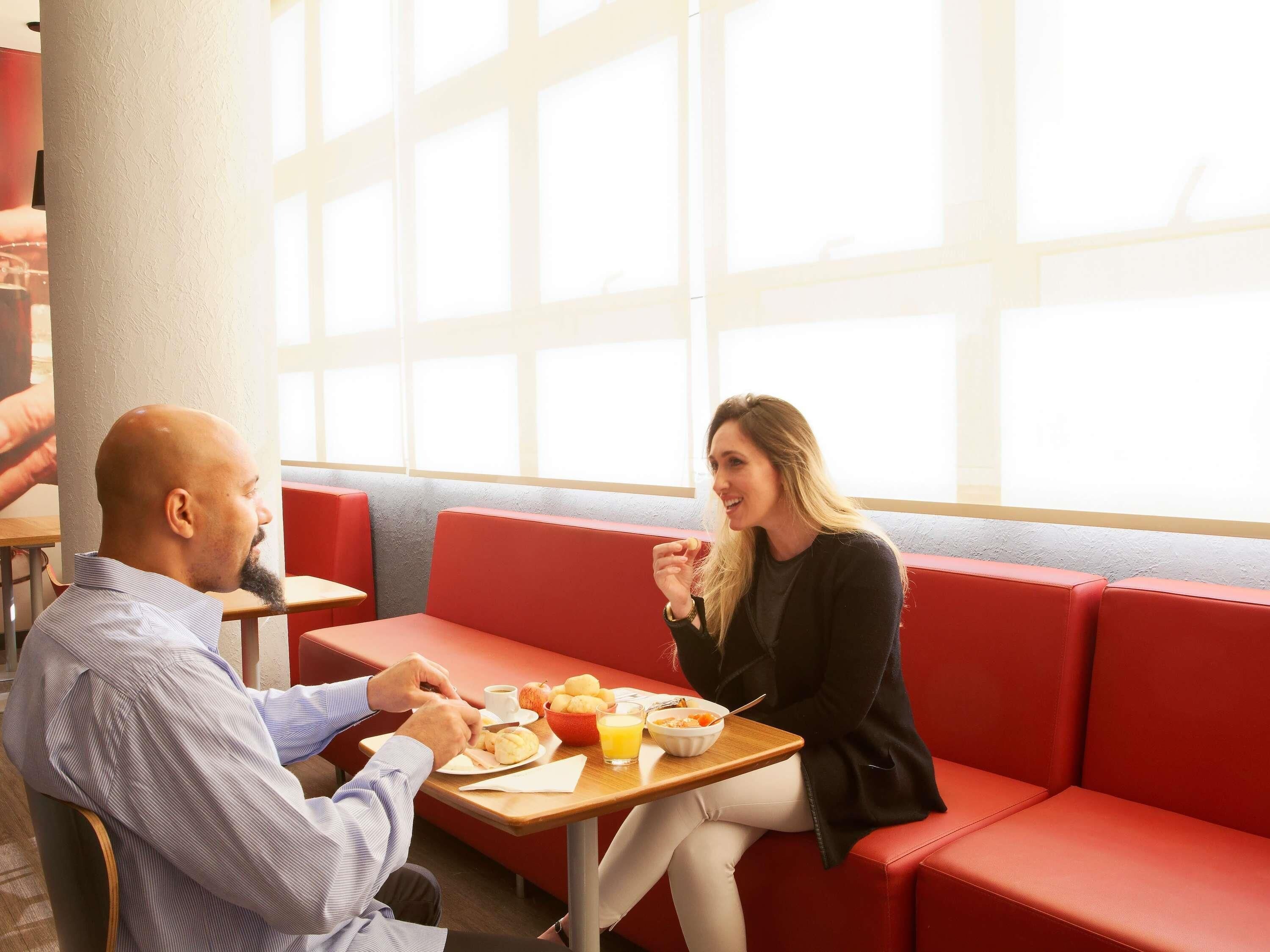 A dining area with red cushioned seating, a wooden table, and a window providing natural light.