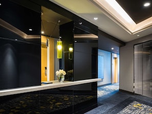 Experience the sleek, contemporary lobby with a long reception desk, large mirror, and unique pendant light fixture.