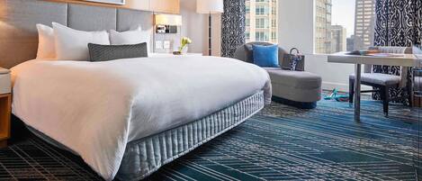 A hotel room with a large bed, a desk, and a view of the city.