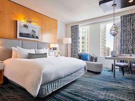 A hotel room with a large bed, a desk, and a view of the city.