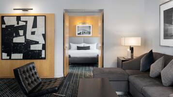 Une chambre d’hôtel comprenant un lit, un canapé, une chaise, une table basse et un grand tableau abstrait.