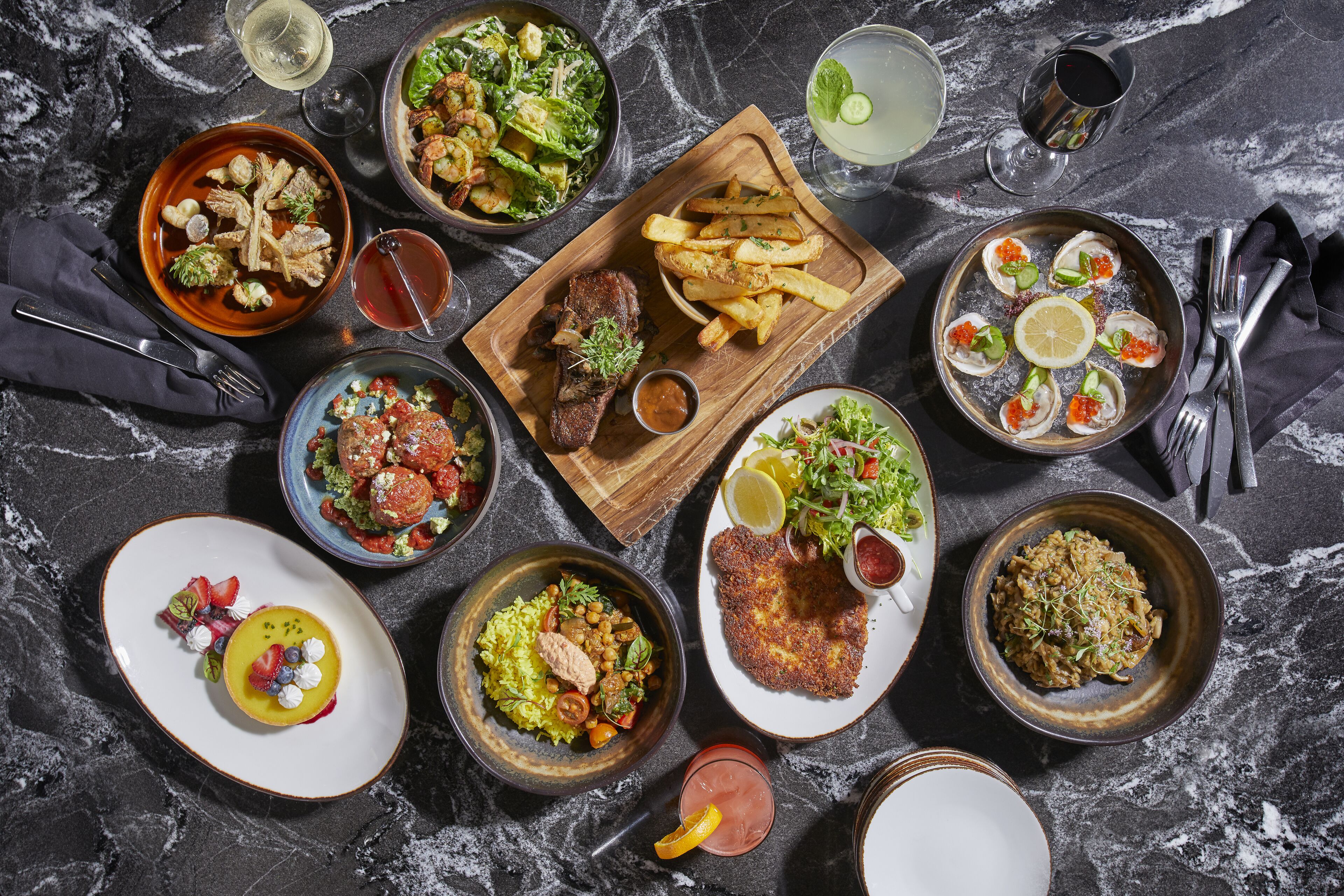 A variety of dishes and drinks on a marble table.