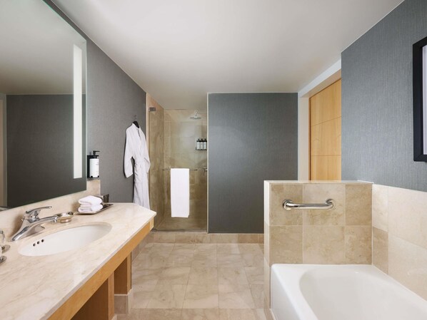 Une salle de bain moderne avec un grand miroir, deux lavabos, une baignoire et un espace douche.