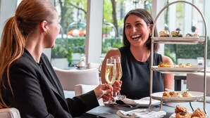 Zwei Personen an einem Tisch mit einer mehrstöckigen Dessertdarbietung und Champagnergläsern.