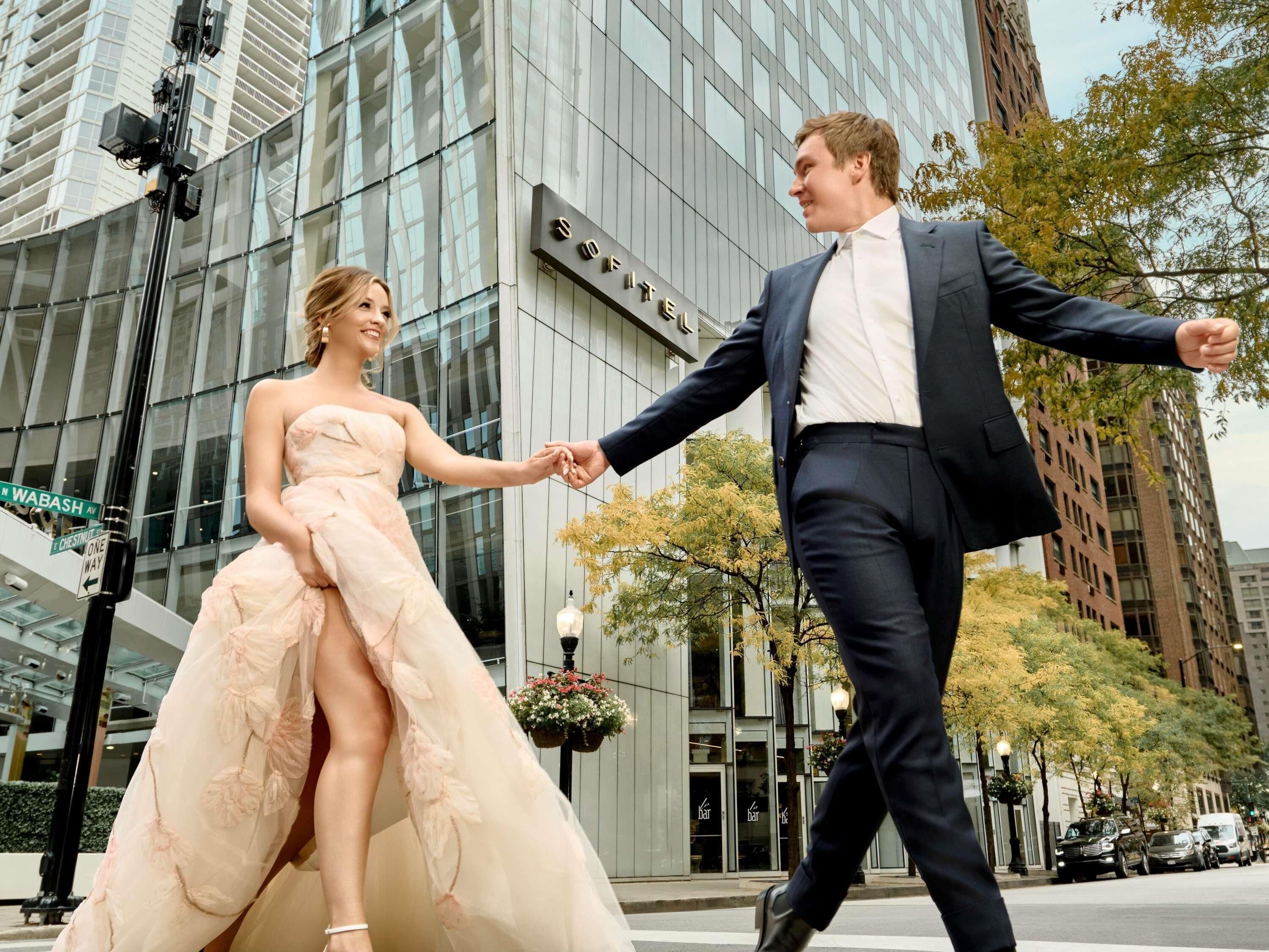 Una pareja tomándose de las manos frente a un edificio moderno con fachada de vidrio.