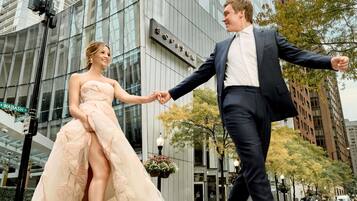 Una pareja tomándose de las manos frente a un edificio moderno con fachada de vidrio.