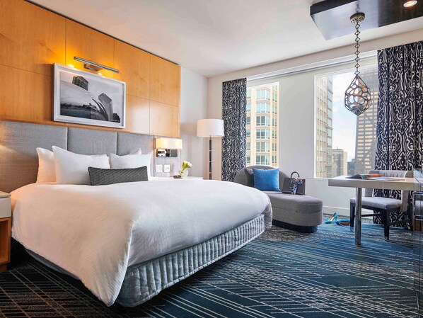 Relax in a spacious room with a large bed, a comfortable chair, and a desk area for work or relaxation.