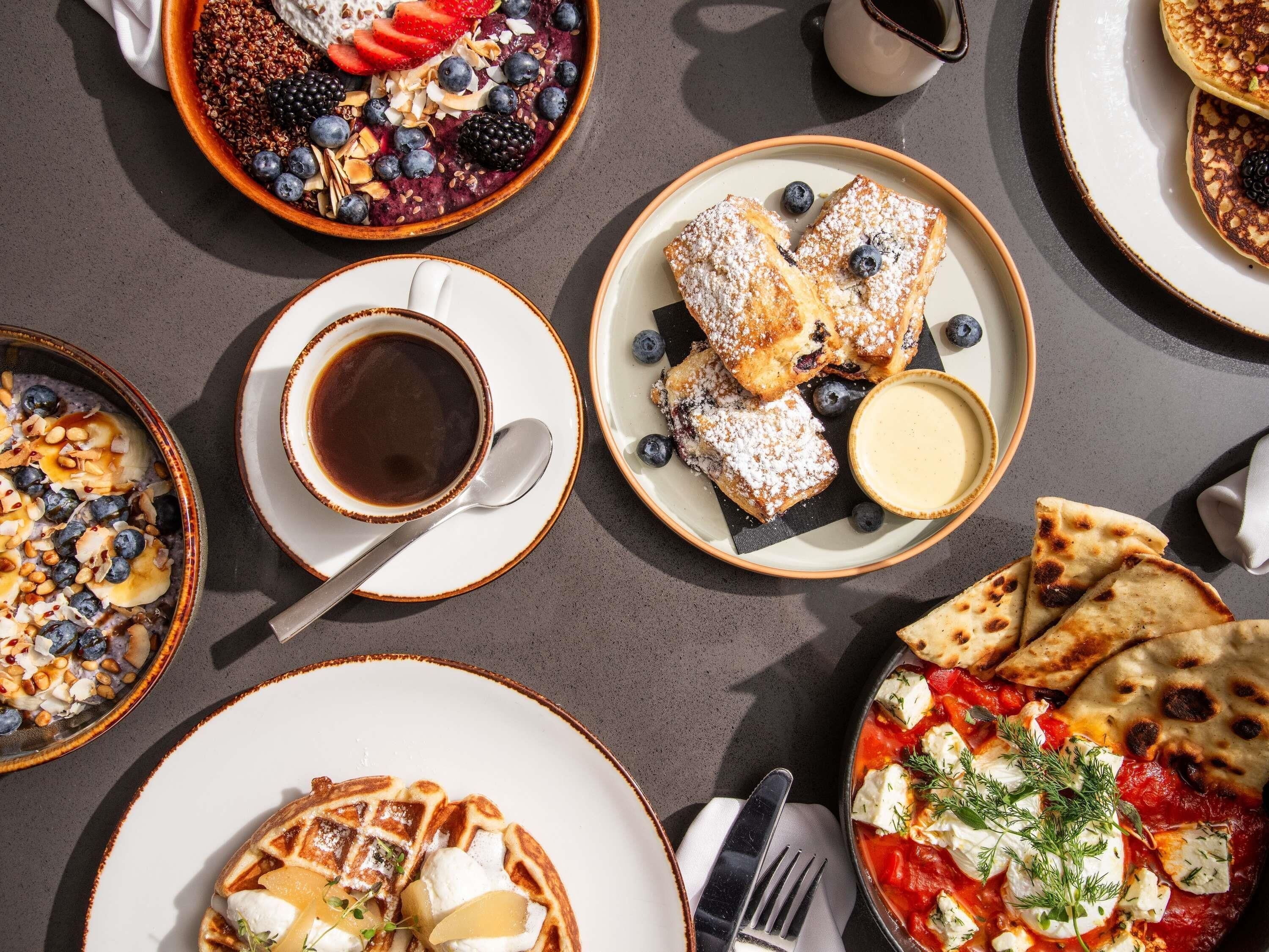 A variety of breakfast dishes including waffles, pancakes, and a bowl of oatmeal topped with fruits and nuts.