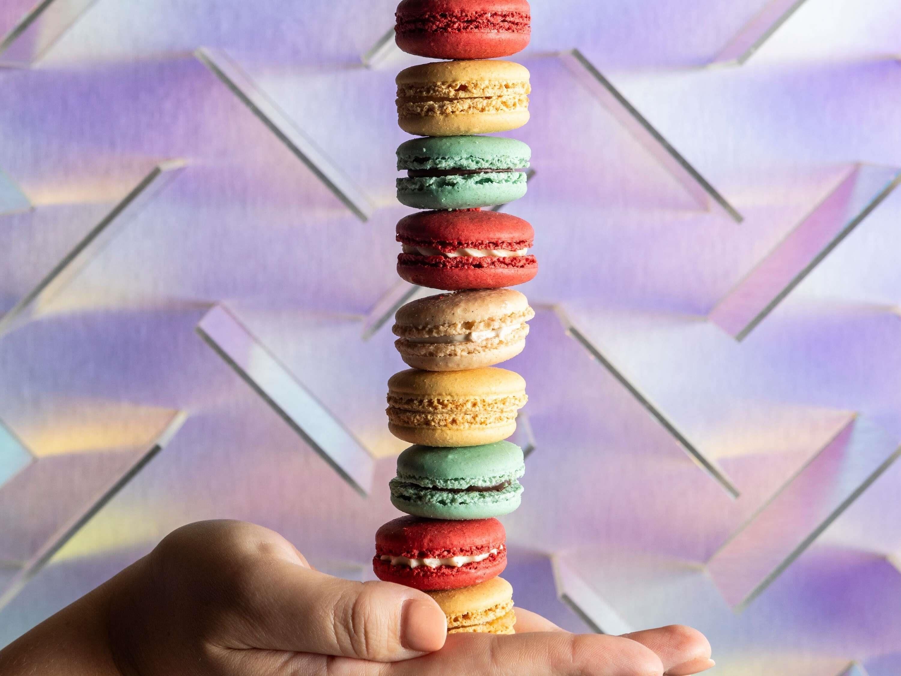 A hand holding a stack of colorful macarons.