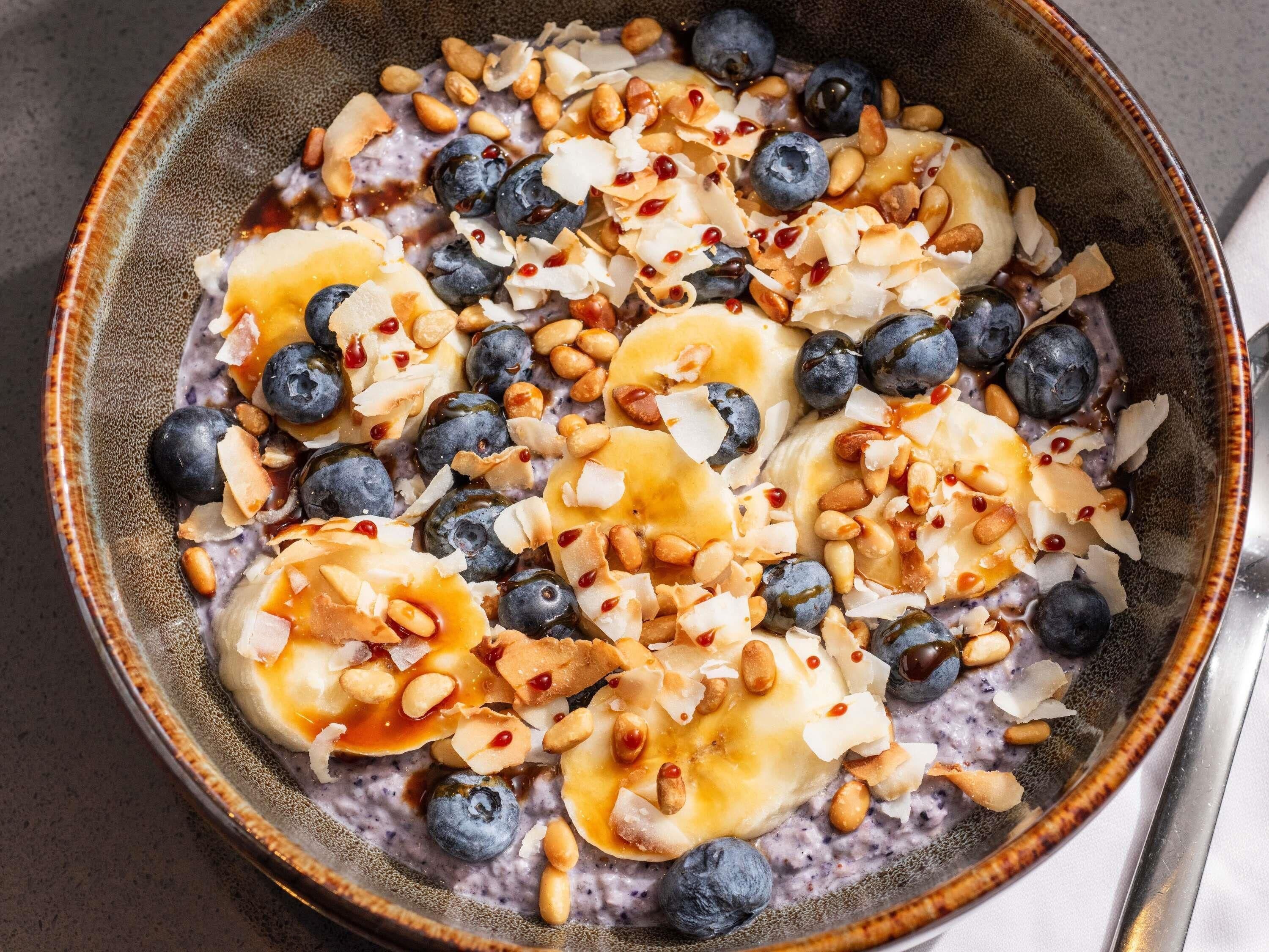Uma tigela de aveia com mirtilos, fatias de banana, amêndoas e lascas de coco.