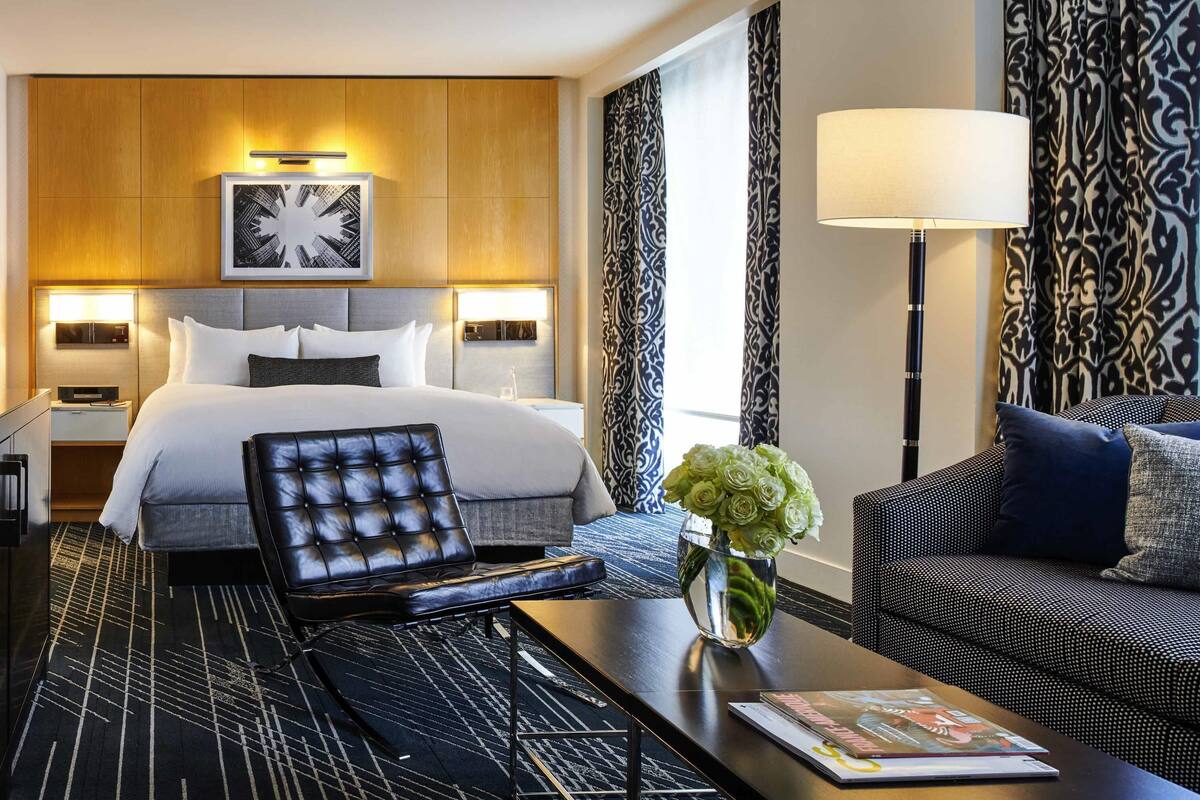 Ein Hotelzimmer mit einem Bett, einem Schlafsofa, einem Couchtisch, einer Lampe und einer Vase mit Blumen.