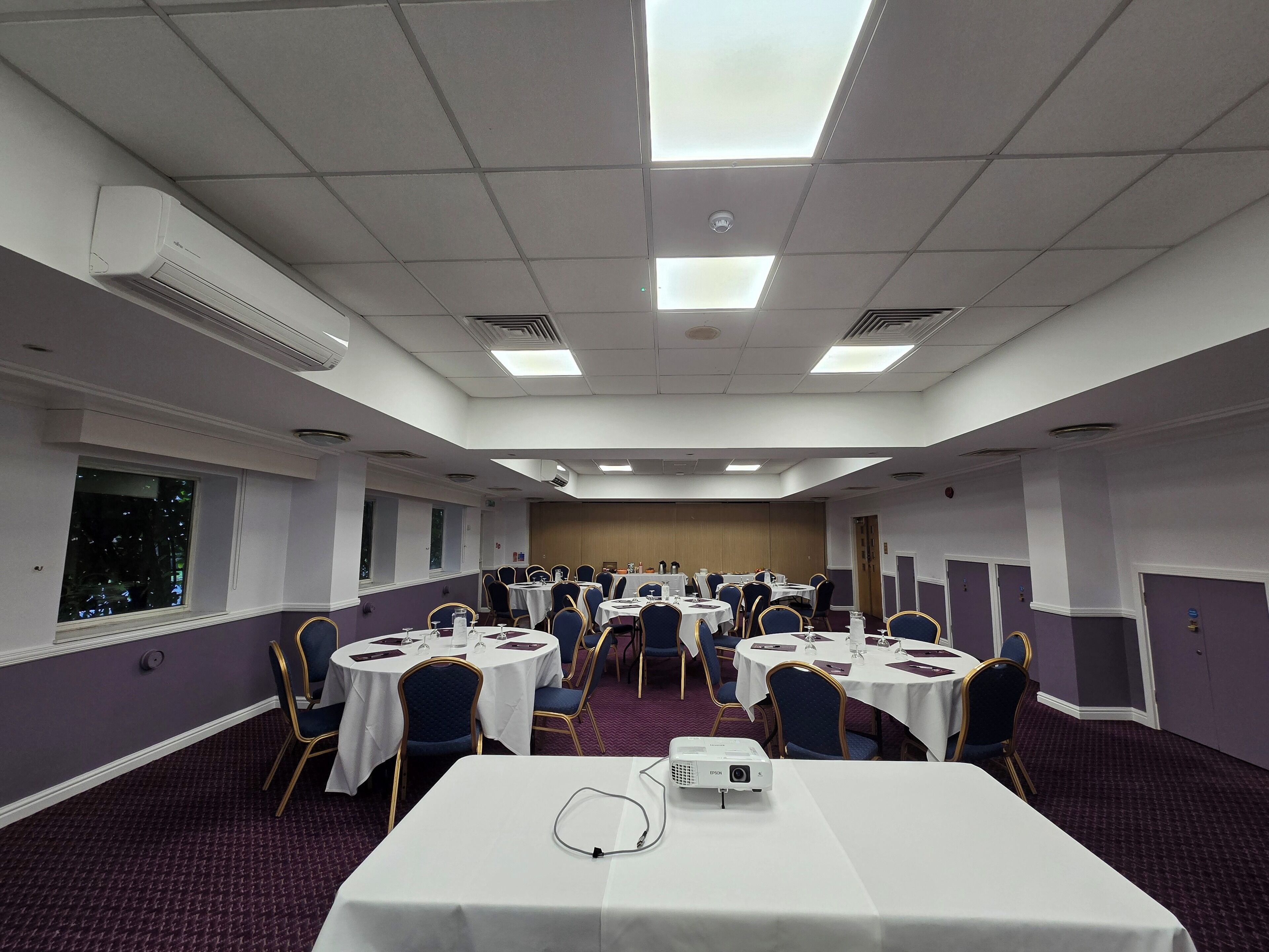 Une salle de conférence équipée de tables rondes, de chaises et d’un projecteur.