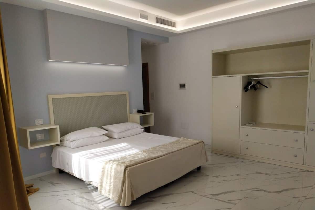 Un dormitorio con cama, mesitas de noche, armario y espejo.