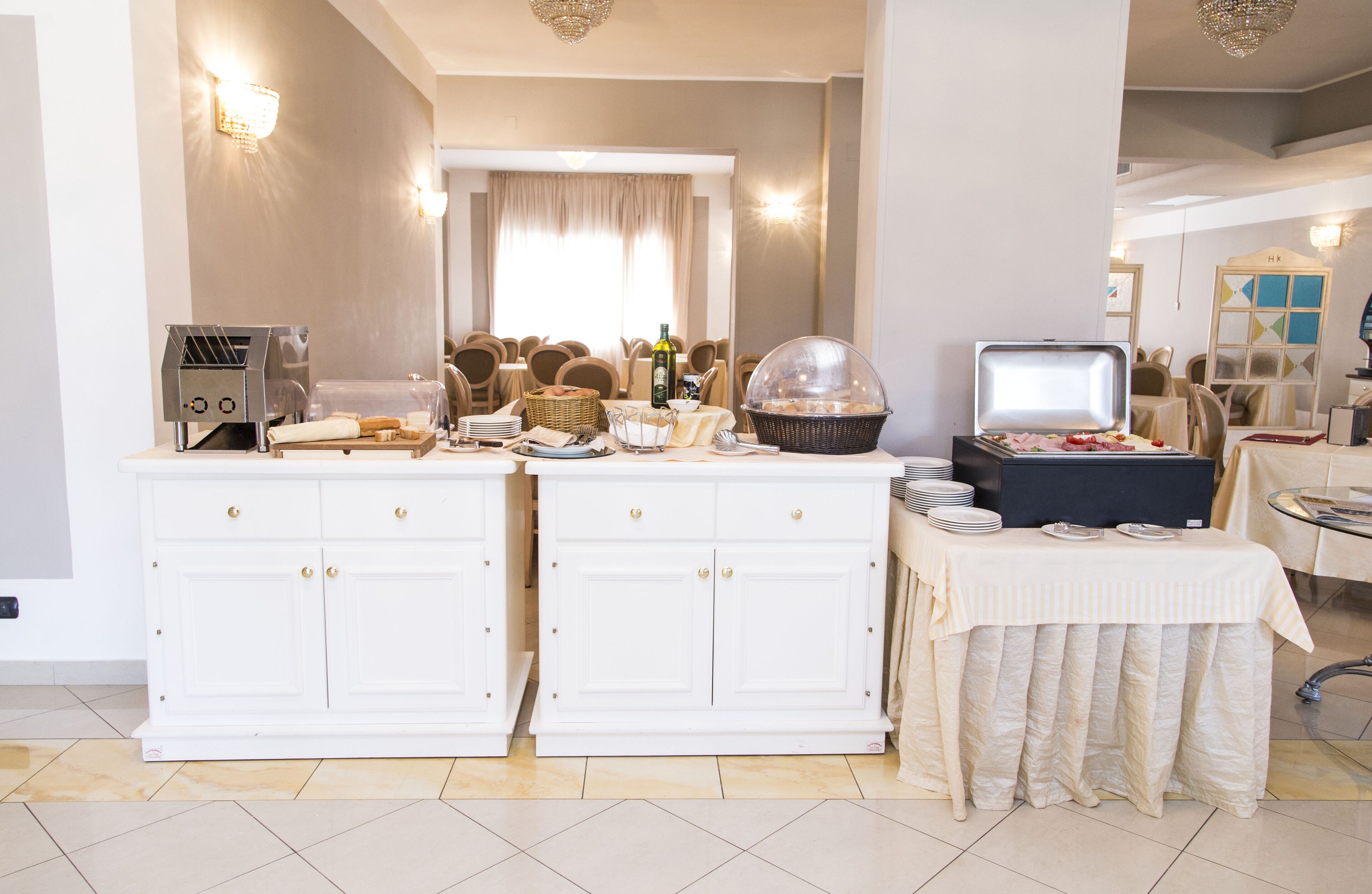 A dining area with a buffet setup, including a bread basket, bottles, and a covered serving station.