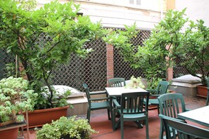An outdoor patio area with a table and chairs, surrounded by potted plants and a lattice fence. - Mokinba Hotels Sant'Ambroeus (Milan)