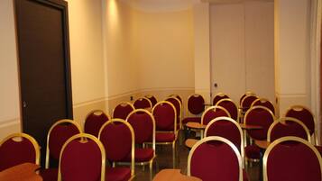 Ein Konferenzraum mit Reihen roter Stühle und Tische, einer Tür und einer weißen Wand.