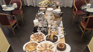 Ein reichhaltiges Buffet mit verschiedenen Speisen, darunter Obst, Gebäck und Getränke.