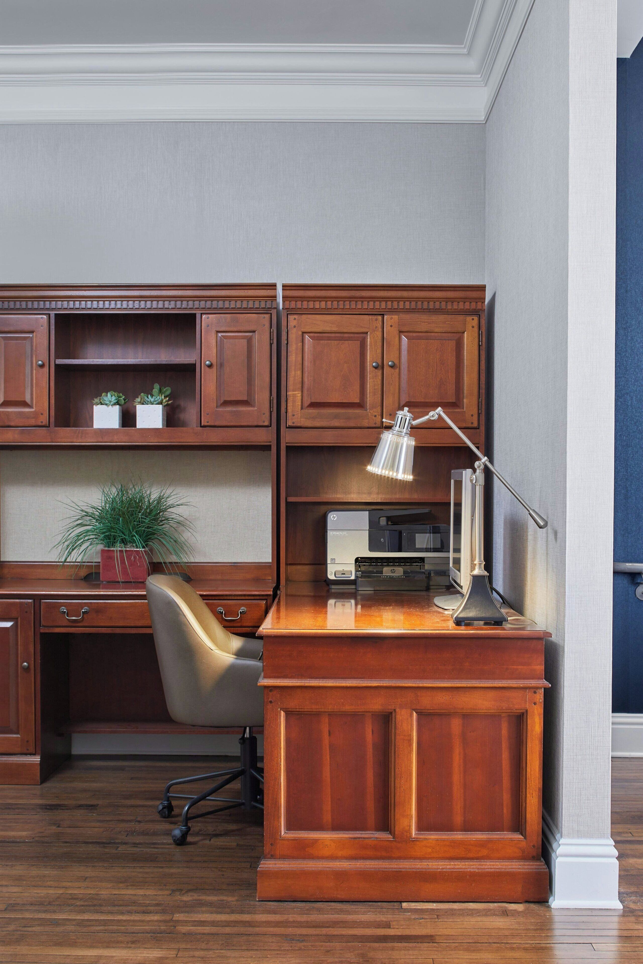 Un bureau en bois, une lampe, une chaise et une imprimante.