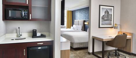 Une chambre d’hôtel équipée d’une kitchenette, d’un lit, d’un bureau et d’une chaise.
