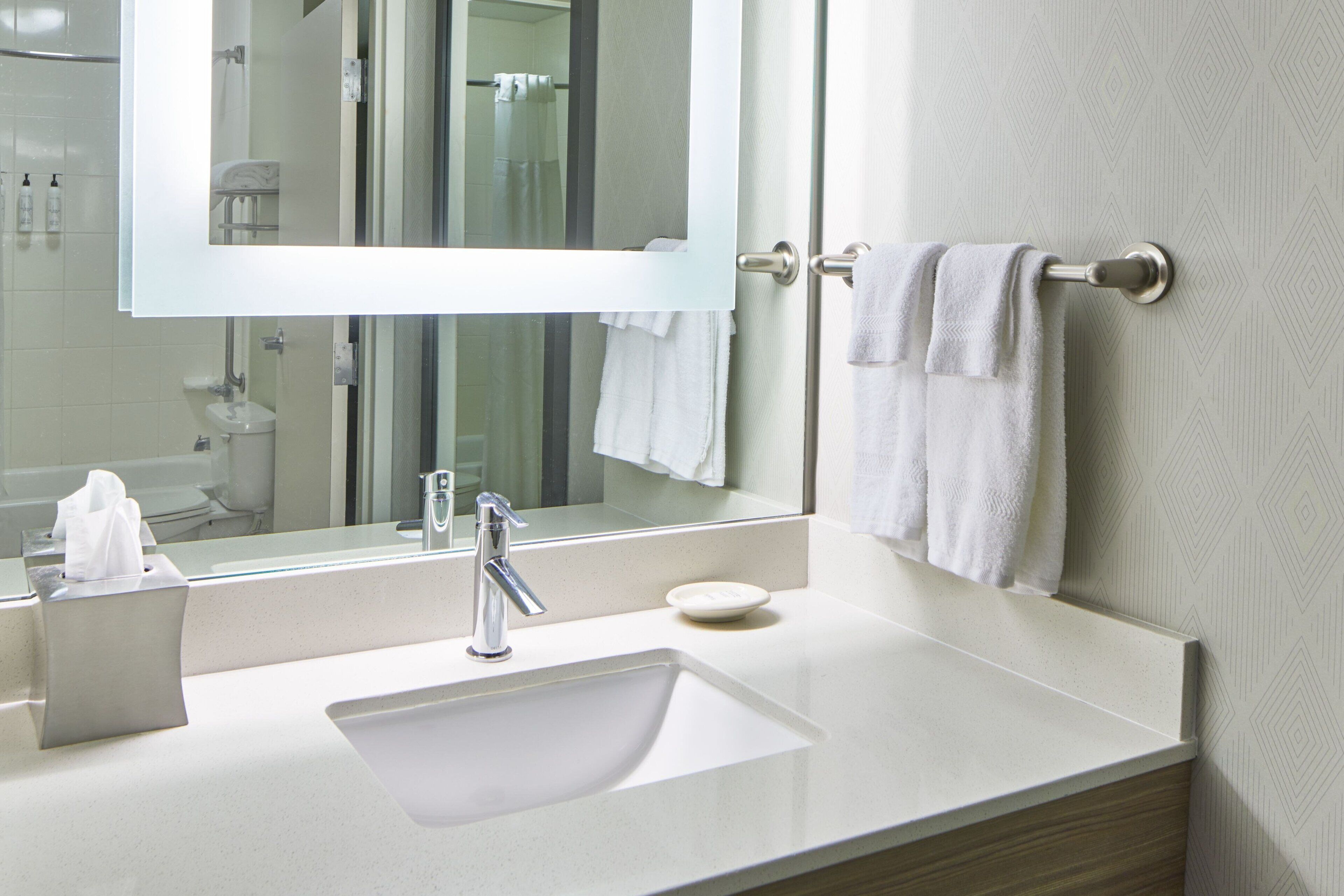 A modern bathroom with a white sink, a mirror, and a towel rack.