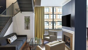 A living room with a sofa, armchairs, a glass coffee table, a fireplace, and a TV. - Springhill Suites By Marriott Memphis Downtown (Memphis)