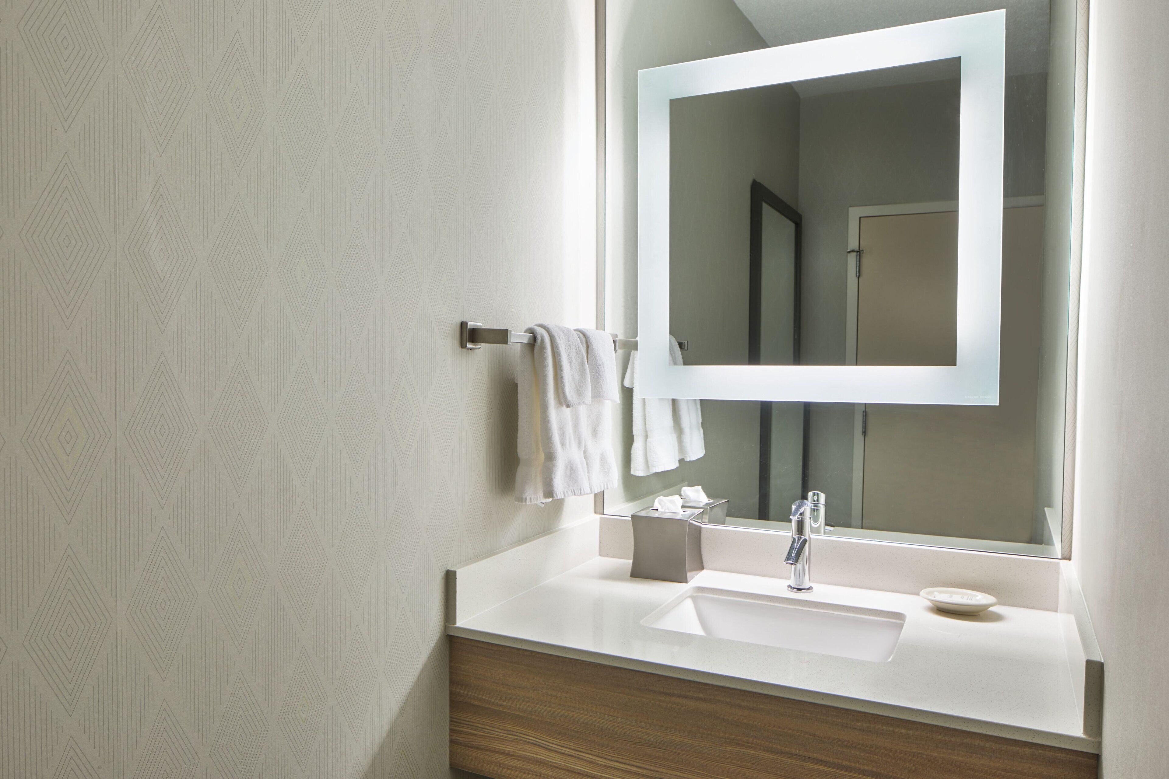 A modern bathroom with a white sink, a mirror, and a towel rack.