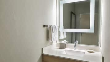A modern bathroom with a white sink, a mirror, and a towel rack.