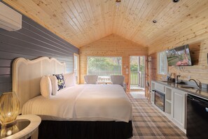 Ein Schlafzimmer in einer Holzhütte mit einem Bett, einem Nachttisch und Blick ins Freie.