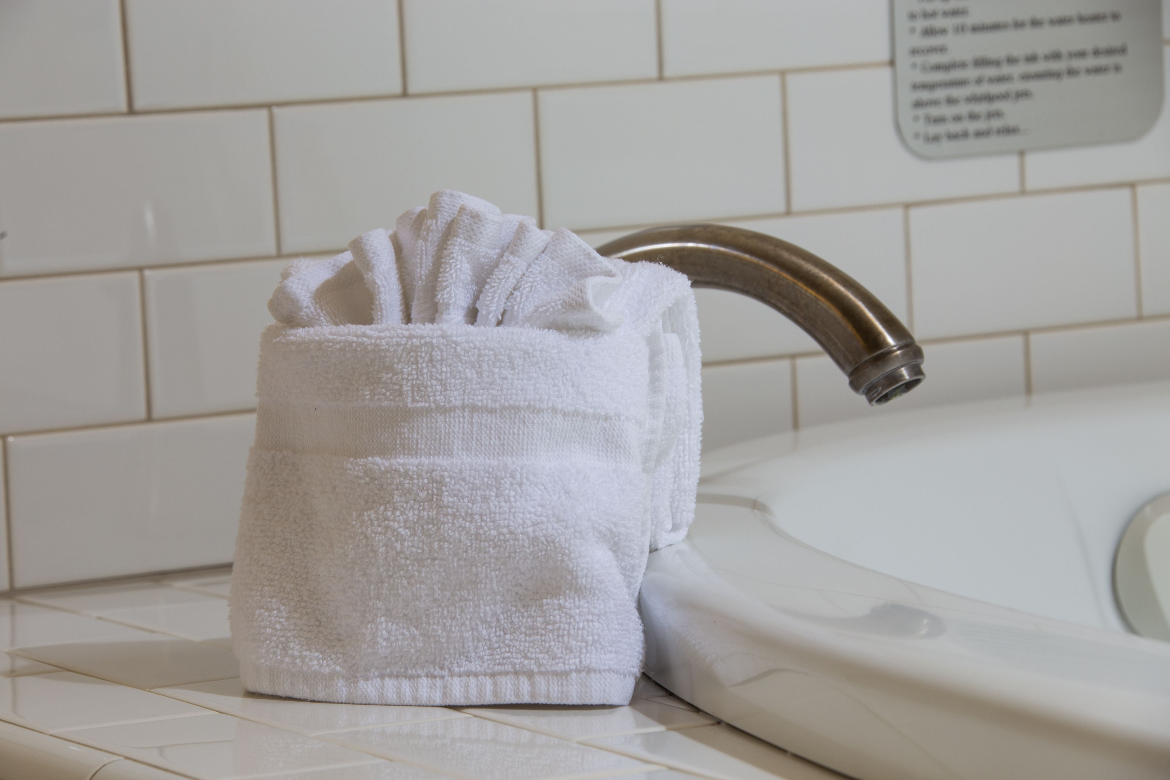 A white towel holder with a towel placed inside, positioned next to a bathroom sink with a chrome faucet.