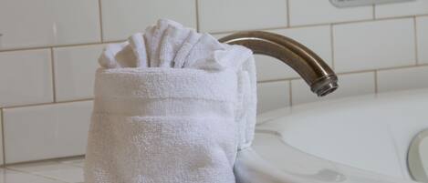 A white towel holder with a towel placed inside, positioned next to a bathroom sink with a chrome faucet.