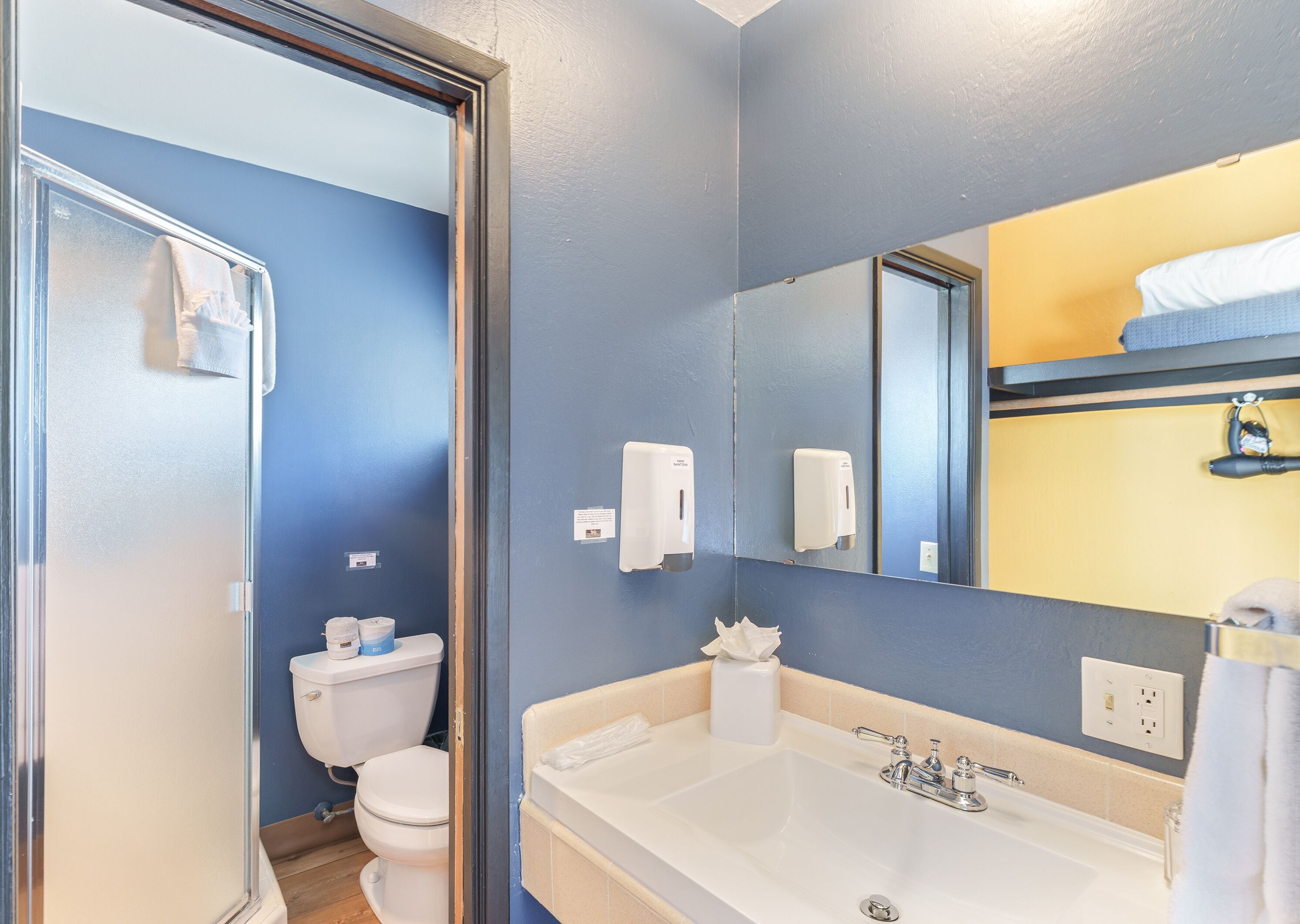 A bathroom with a white sink, a mirror, and a toilet.