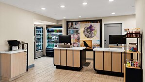 A modern reception area with a counter, a refrigerator stocked with beverages, and a wall with a bird painting. - Sonesta ES Suites San Diego - Sorrento Mesa (San Diego)