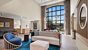 A spacious living area with a large window, a sofa, a chair, and a coffee table. - Sonesta ES Suites San Diego - Sorrento Mesa (San Diego)