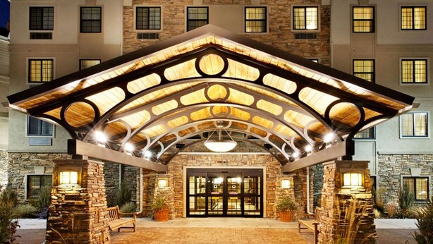 A hotel entrance with a stone facade, a covered patio area, and a large glass door. - Sonesta ES Suites San Diego - Sorrento Mesa (San Diego)