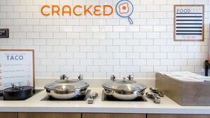A kitchen counter with two stainless steel food warmers, a sign for 'CRACKED' with a magnifying glass, and a 'Today's Menu' board. - Sonesta ES Suites San Diego - Sorrento Mesa (San Diego)