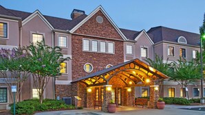 A multi-story hotel with a stone facade, a covered entrance area with seating, and a parking lot. - Sonesta ES Suites San Diego - Sorrento Mesa (San Diego)
