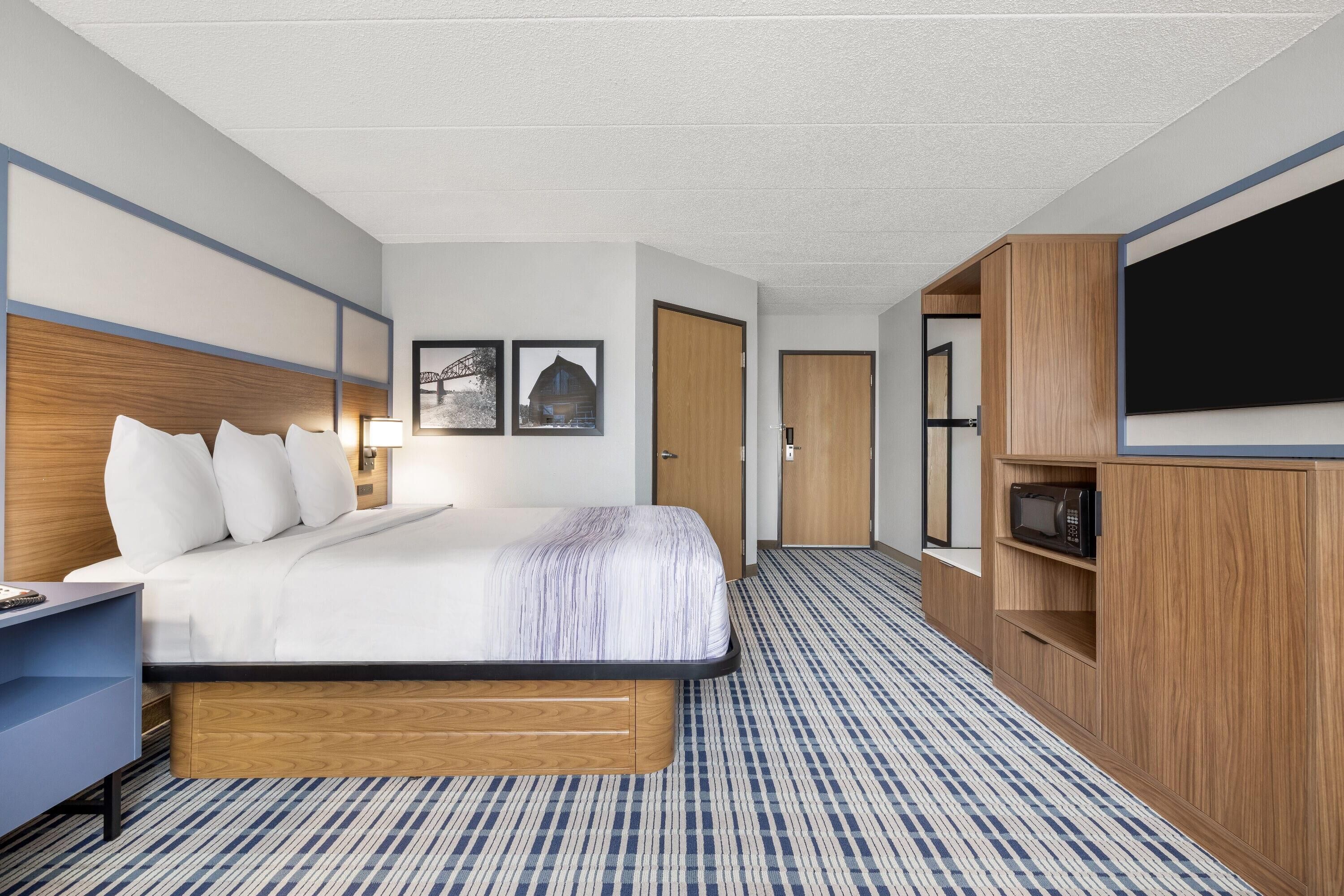 Una habitación de hotel con cama, escritorio, televisor y armario.