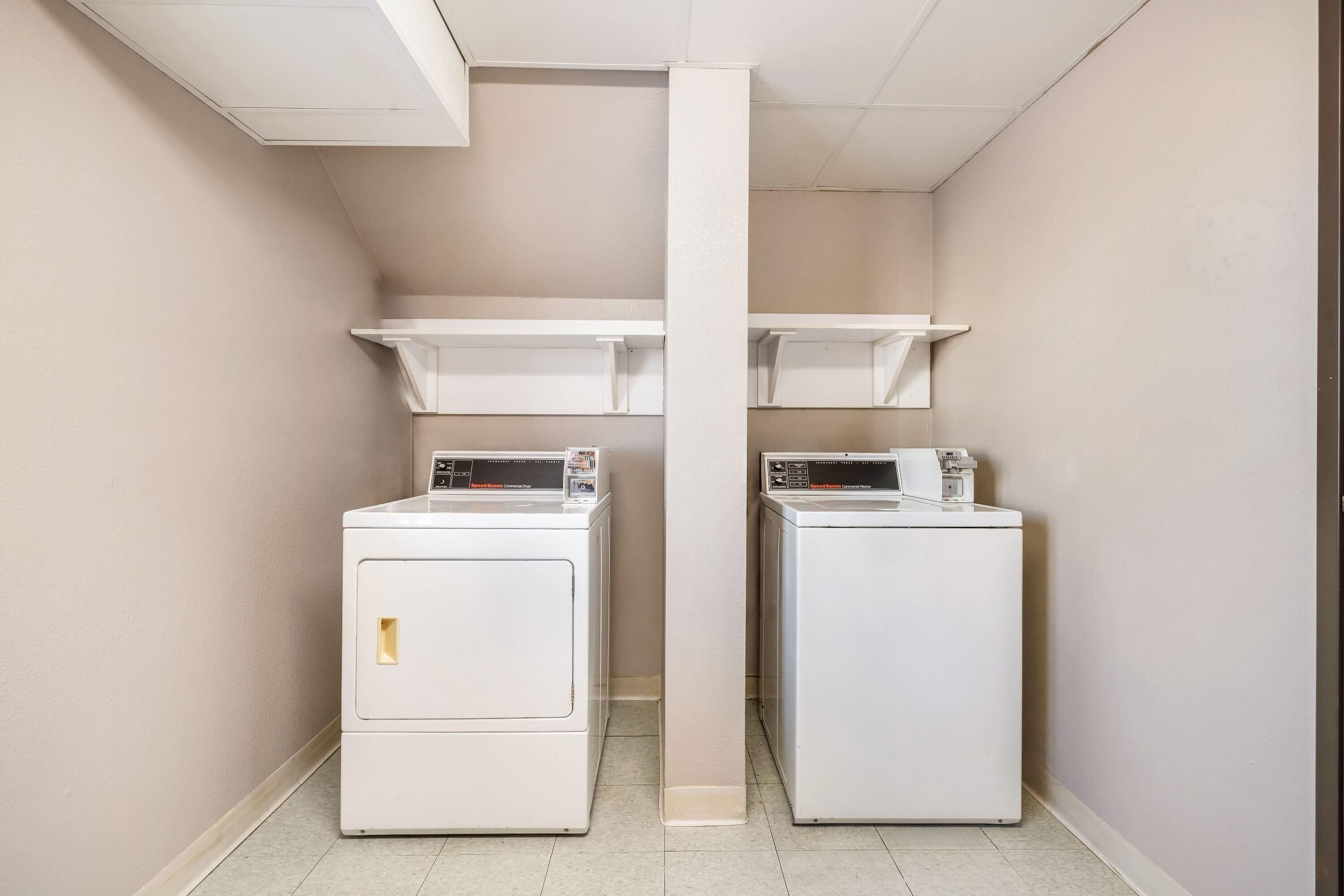 A laundry room with two white front-loading washing machines and a central white pillar.