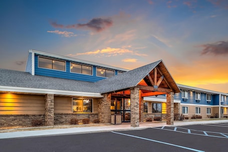 A hotel with a covered entrance, multiple windows, and a parking lot.