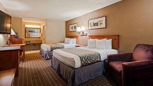 Ein Hotelzimmer mit zwei Betten, einem Schreibtisch, einem Stuhl, einem Spiegel und Bildern an der Wand.