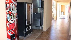 Ein Flur mit einem Automaten, zwei Kühlschränken und einem gefliesten Boden.